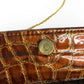 Close-up of a brown textured clutch bag with a gold button and strap.