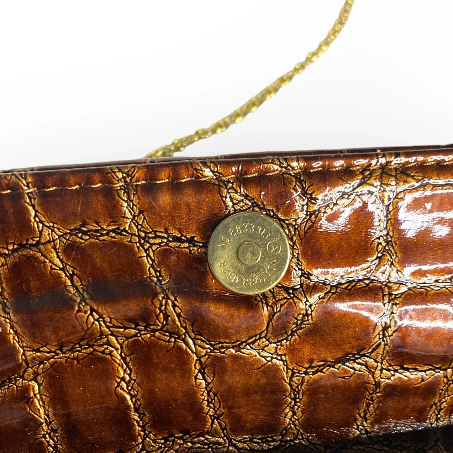 Close-up of a brown textured clutch bag with a gold button and strap.