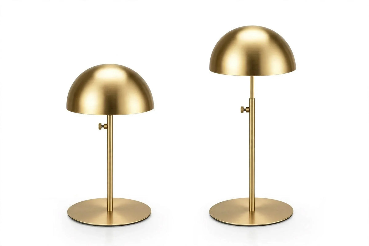 Two gold dome-shaped metal table lamps with slim stands on a white background