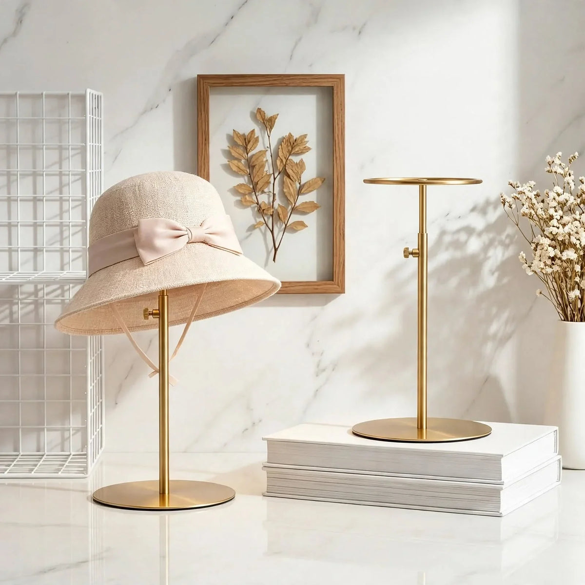 Beige straw sun hat with a bow on a gold metal hat stand against a marble background