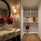 Red, gold, and straw wigs displayed in a modern dressing area with marble countertops.